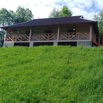 Котедж з верандою на зеленому пагорбі садиби влітку