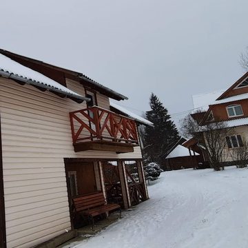 Будинки садиби взимку: білий будинок з червоним балконом, сніг на подвір’ї, смерека